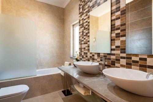 Un baño con dos lavabos, una bañera y un inodoro. en Villa Belchior, en Faro