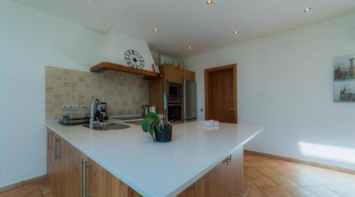 a kitchen with a white counter top and wooden cabinets at Villa Areias II - Beautiful landscape garden in Estói