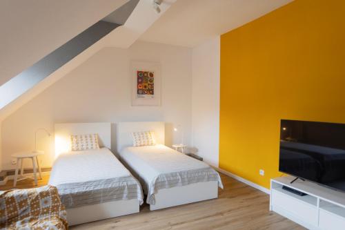 two beds in a room with a yellow wall at Big flat with fresh renovation, free parking, SonyPS, Netflix in Duisburg