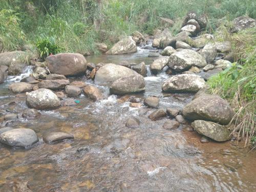 a stream of water with rocks andgrass at Rock View Holiday Bungalow in Matale