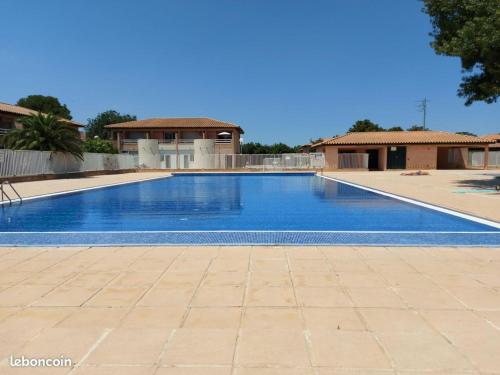 une grande piscine bleue devant une maison dans l'établissement L'Oasis de Jade - T2 avec terrasse - Piscine, à Saint Cyprien Plage