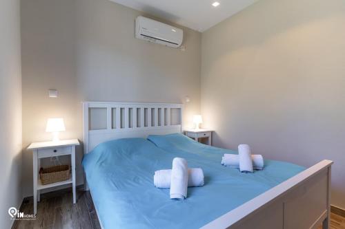 a white bedroom with a blue bed with two pillows at 'Red Port'Amazing House 5 min from the sea in Rafina