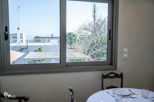 a table with two windows looking out at a balcony at 'Red Port'Amazing House 5 min from the sea in Rafina