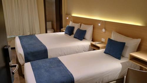 two beds in a hotel room with blue pillows at Pacifico Hotel in Buenos Aires