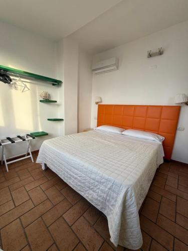 a bedroom with a large bed with an orange headboard at Tropea Boutique Hotel in Tropea