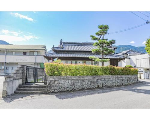 a house with a stone wall in front of a building at Minka -STAY Traditional Japanese houses in Miyoshi