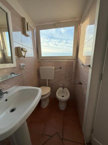 a bathroom with a sink and a toilet and a window at Tropea Boutique Hotel in Tropea
