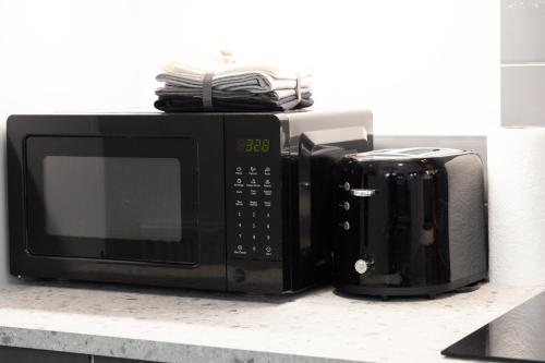 two microwaves sitting on top of a kitchen counter at Private ensuite rooms with kitchen access by Irwell Stays in Manchester