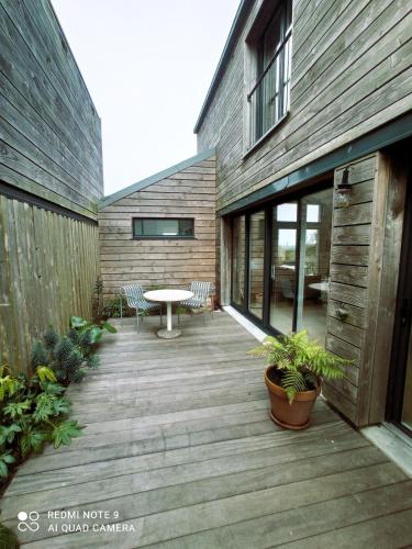 une terrasse en bois avec une table et des chaises dans un bâtiment dans l'établissement Maison avec jardin à 10 minutes à pied de la plage, à Batz-sur-Mer