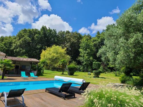 une terrasse avec un canapé bleu et des chaises près de la piscine dans l'établissement Le Domaine des Doucins & Spa, Gîte 4 étoiles, 10 minutes de Jonzac piscine et spa, à Fontaines-dʼOzillac