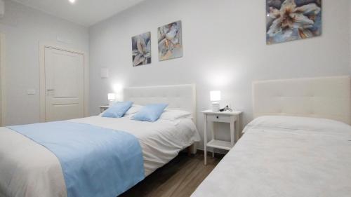 two beds in a white bedroom with blue pillows at Black Horse in San Giorgio a Cremano