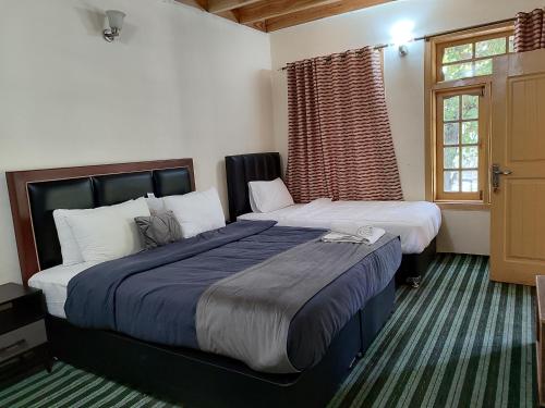 a bedroom with two beds and a window at Grapes Garden Resort Hunza in Hunza Valley