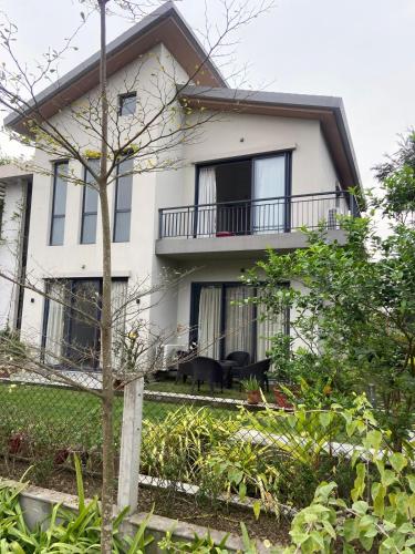 a white house with a balcony and a tree at A perfect place to be in nature in Kolkata