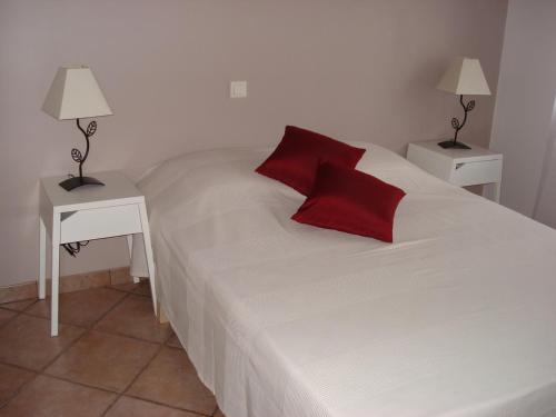 - une chambre avec un lit blanc et des oreillers rouges dans l'établissement Maison avec terrasse, à Saint-André-de-Sangonis