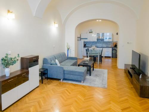 Una sala de estar con un sofá azul y una cocina. en Luxury Vincents Apartments Kosice, en Košice