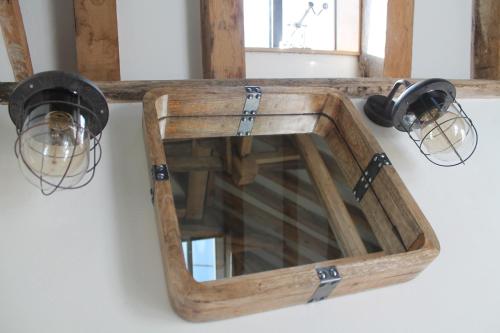 a wooden mirror hanging on a wall with lights at The Dovecote - unique self-contained 1bed renovated barn in Saffron Walden