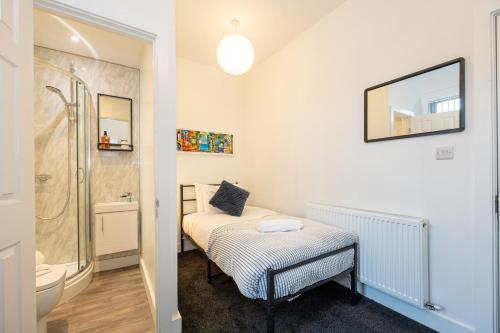 a small bathroom with a bed and a shower at Private ensuite rooms with kitchen access by Irwell Stays in Manchester