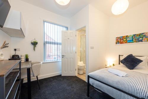 a bedroom with a bed and a desk and a sink at Private ensuite rooms with kitchen access by Irwell Stays in Manchester