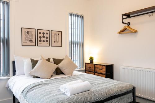 a white bedroom with a large bed with pillows at Private ensuite rooms with kitchen access by Irwell Stays in Manchester