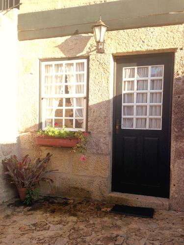 a house with a black door and two windows at Casa de Abbades in Ponte de Lima