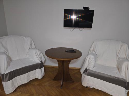 a room with two chairs and a table and a tv at CATTALEYA in Batumi