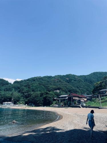un homme se promenant sur une plage près de l'eau dans l'établissement 民宿上田屋, à Obama