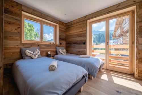 - 2 lits dans une chambre dotée de murs en bois et de fenêtres dans l'établissement Appartement Gritti - Megève, à Megève