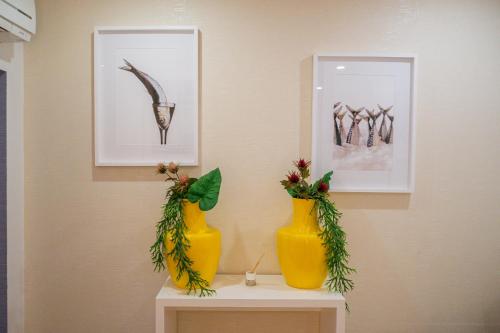 two yellow vases on a table with pictures on the wall at By the Sea - Nazaré in Nazaré