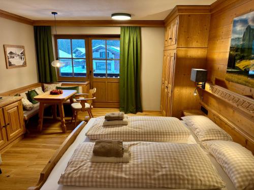 a bedroom with two beds and a table and a desk at Alpennest Blindau in Reit im Winkl
