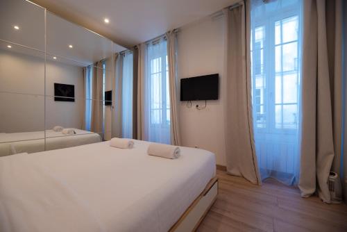 une chambre avec un grand lit blanc et une télévision dans l'établissement CIA - Réaumur Étienne Marcel 4P, à Paris