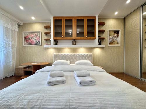 a bedroom with a large white bed with towels on it at ApartPoltava Стильна квартира біля Білої Альтанки, серце Полтави in Poltava