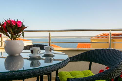 a table and chairs with a vase and flowers on a balcony at Apartments Topli Bok in Trogir