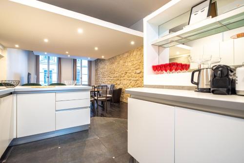 - une cuisine avec des placards blancs et un mur en pierre dans l'établissement CIA - Réaumur Étienne Marcel 8P, à Paris