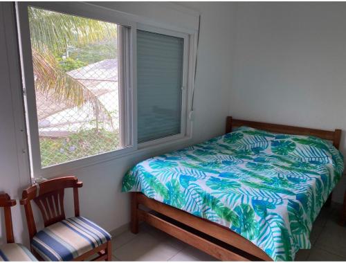 a bedroom with a window with a bed and a chair at Beautiful house Juquehy in São Sebastião