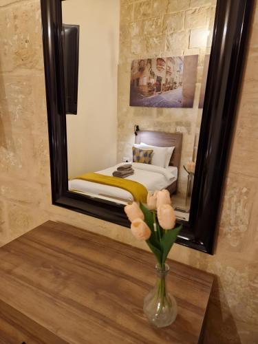 a vase of flowers on a table in front of a mirror at Ancient Maltese House with modern interior 3 min away from Airport TAL-PINU in Gudja