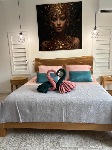 Dos flamencos están sentados encima de una cama. en Au domaine du commandant, en Bouillante
