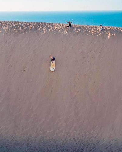 a man riding a snowboard on a sandy beach at Argan House Morocco in Taghazout