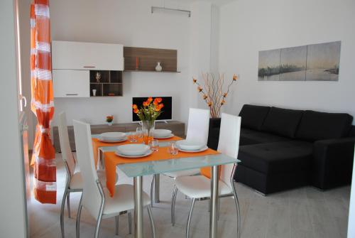 a dining room table with white chairs and a black couch at Sesto Piano House in Monopoli