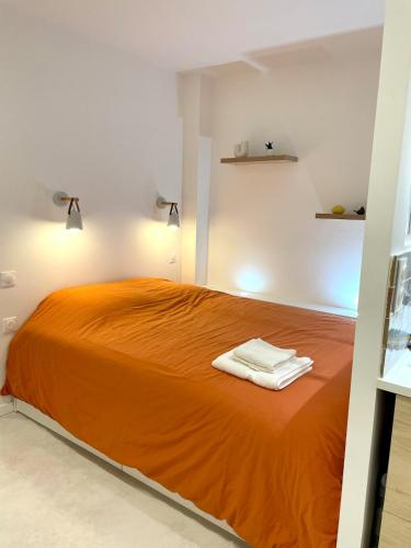 a bedroom with an orange bed with two towels on it at Studio ultra centre libourne - jacuzzi & vidéoprojecteur in Libourne