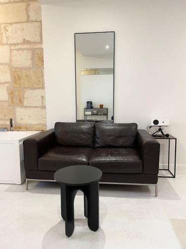 a black leather couch with a table and a mirror at Studio ultra centre libourne - jacuzzi & vidéoprojecteur in Libourne
