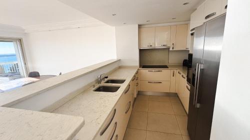 La cuisine est équipée de comptoirs blancs et d'un réfrigérateur en acier inoxydable. dans l'établissement Appartement 2 chambres - Vue panoramique, à Cannes