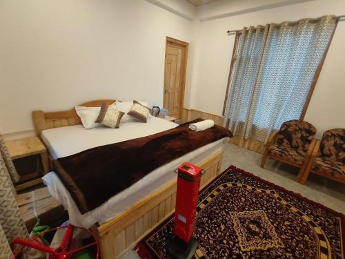 a bedroom with a large bed and a red vacuum at Shreya cozy hut in Sainj