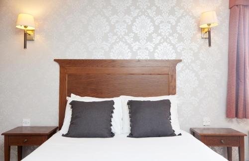 a bedroom with a white bed with two night stands and two lamps at Castle Inn by Greene King Inns in Bakewell