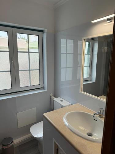 a bathroom with a sink and a toilet and a mirror at Casa Estrelinha Vilamoura in Quarteira