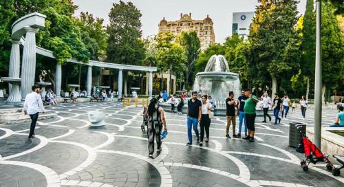 a group of people standing around a fountain in a park at Aden City Hotel in Baku