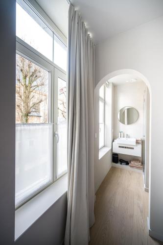 a white bathroom with a sink and a window at Istoire in Bruges