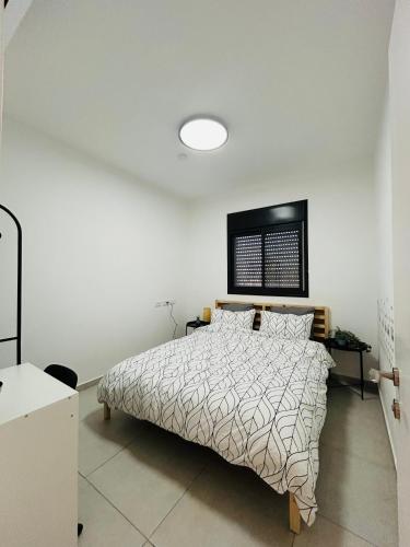 a bedroom with a bed and a white wall at הפנינה השחורה in Mitzpe Ramon
