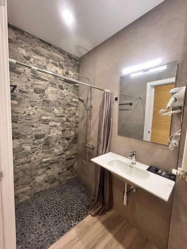 a bathroom with a sink and a stone wall at Apartaco Apartamentos in Sitges