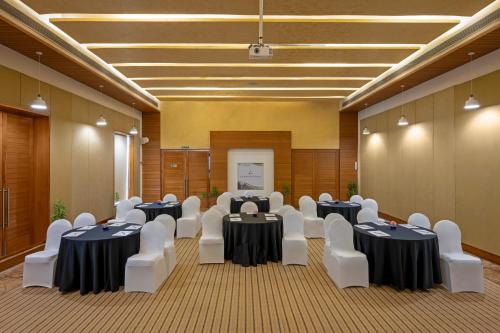 a conference room with tables and white chairs at Club Mahindra Kensville in Ahmedabad