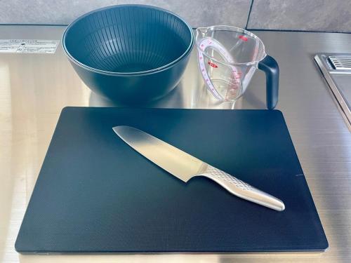 a knife sitting on a cutting board next to a cup at GARDENIA Sunset in Takamatsu